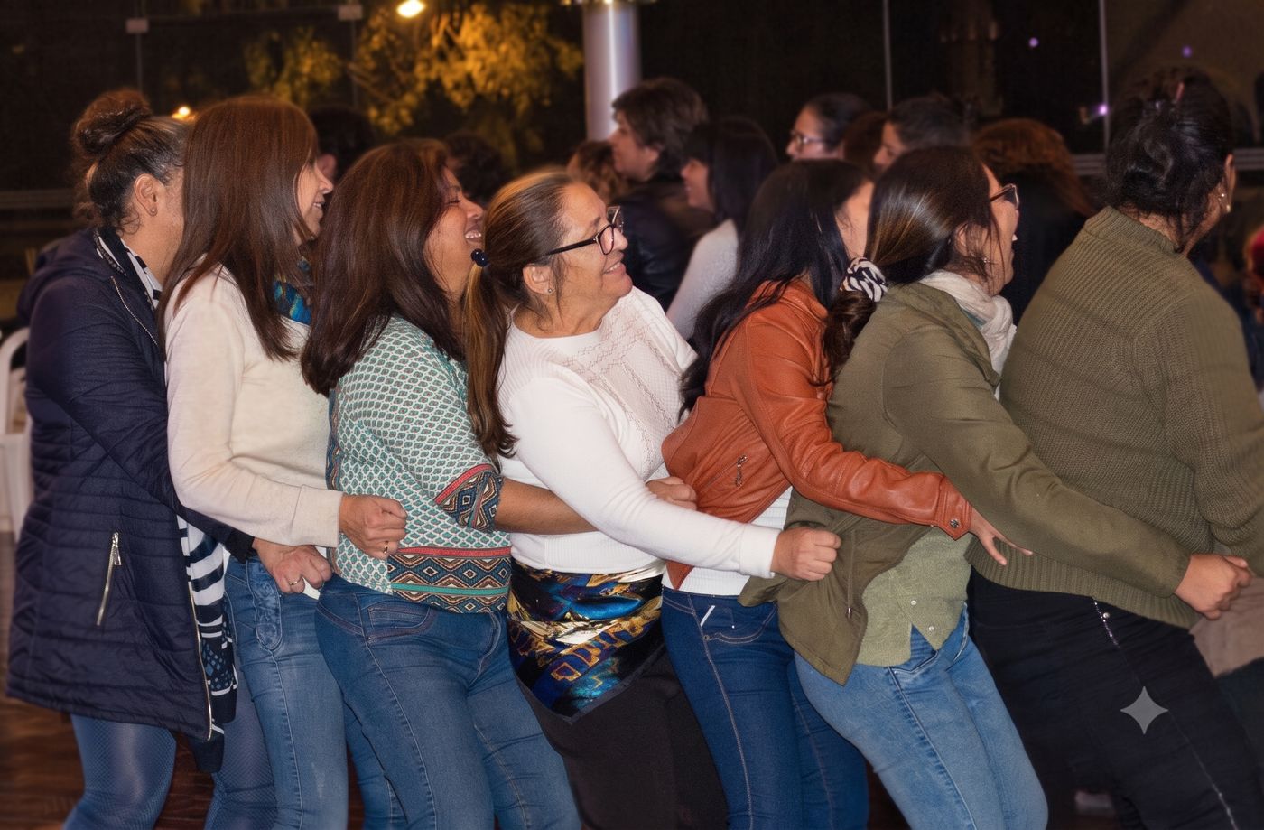 Participantes tomados del brazo en movimiento grupal durante taller vivencial