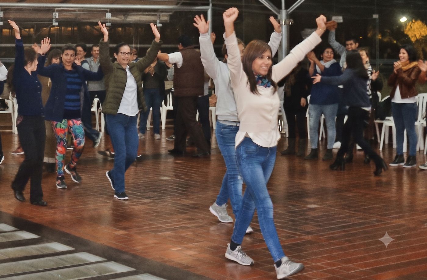 Participantes celebrando con los brazos en alto en taller de bienestar